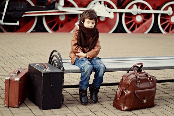 Boy waiting at train station with suitcases